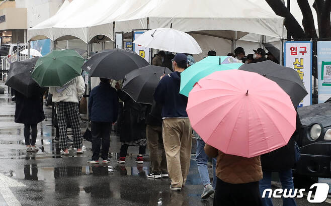 14일 오후 서울 동작구청에 마련된 신종 코로나바이러스 감염증(코로나19) 임시선별진료소에서 우산을 쓴 시민들이 검사를 받기 위해 줄을 서고 있다. 2022.3.14/뉴스1 © News1 구윤성 기자