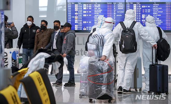 [인천공항=뉴시스] 정병혁 기자 = 정부가 오는 21일부터 코로나19 백신 접종을 완료한 해외입국자를 대상으로 자가격리를 면제하고, 국내 면세점 구매 한도를 없애는 등의 조치로 해외여행 수요가 늘어날 것으로 예측된 지난 20일 오전 인천국제공항 1터미널 출국장에서 기념촬영을 하고 있는 공항 이용객 옆으로 방호복을 입은 승객이 대기하고 있다. 2022.03.21. jhope@newsis.com