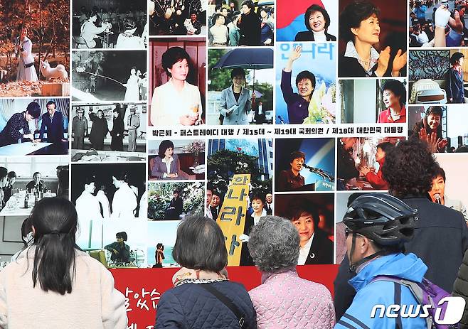 박근혜 전 대통령 귀향과 입주를 하루 앞둔 23일 오후 지지자들이 사저 앞 게시대에 전시된 박 전 대통령 사진을 살펴보고 있다. 2022.3.23/뉴스1 © News1 공정식 기자