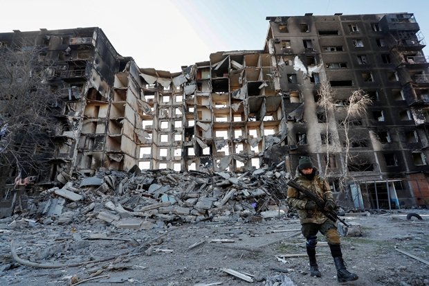 28일(현지시간) 친러군 병사가 우크라이나 남부 항구도시 마리우폴에서 러시아의 포격으로 파괴된 아파트 근처를 걷고 있다. 이날 마리우폴 시장은 도시가 사실상 러시아군 손에 넘어갔다고 밝혔다./로이터 연합뉴스