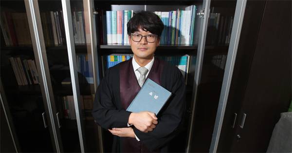 신동주 수원고등법원 판사가 보호소년 재판에 관한 실무서를 들고 웃고 있다. 신 판사는 드라마 `소년심판` 대본 자문을 요청받고 보호소년의 모습을 알릴 수 있는 좋은 기회라고 생각해 자문료를 받지 않고 감사한 마음으로 참여했다고 말했다. [이승환 기자]