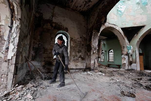6일(현지시간) 우크라이나 수도 키이우 북쪽으로 약 100㎞ 떨어진 도시 체르니히우에서 한 청년이 러시아군 폭격으로 폐허가 된 마을을 청소하고 있다./로이터 연합뉴스