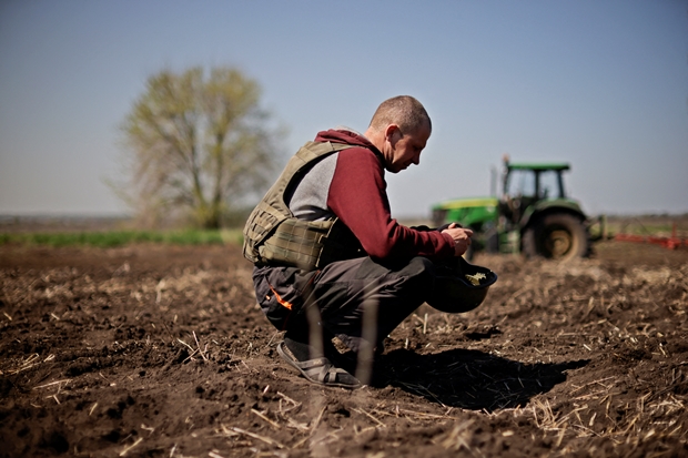 26일(현지시간) 우크라이나 남동부 자포리자에서 농부 올레크시이가 방탄모를 잠시 벗고 들판에 쭈그려 앉아 있다./로이터 연합뉴스