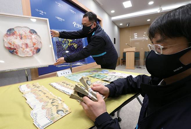 서울특별시 38세금징수과 직원이 2021년 3월 서초구 최순영 전 신동아그룹 회장 자택에서 압수한 현금과 미술품을 시청 브리핑룸에서 공개하고 있다.ⓒ연합뉴스