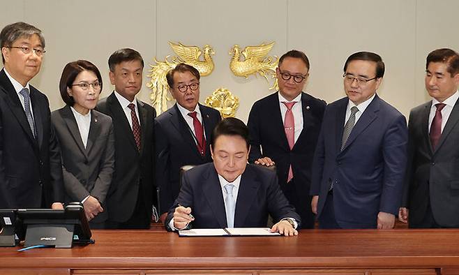 윤석열 대통령이 10일 서울 용산에 새로 마련된 대통령 집무실에서 1호 법안에 서명하고 있다. 뒷줄 왼쪽부터 김대기 비서실장, 강인선 대변인, 최상목 경제수석, 최영범 홍보수석, 안상훈 사회수석, 김성한 국가안보실장, 김용현 대통령경호처장. 연합뉴스