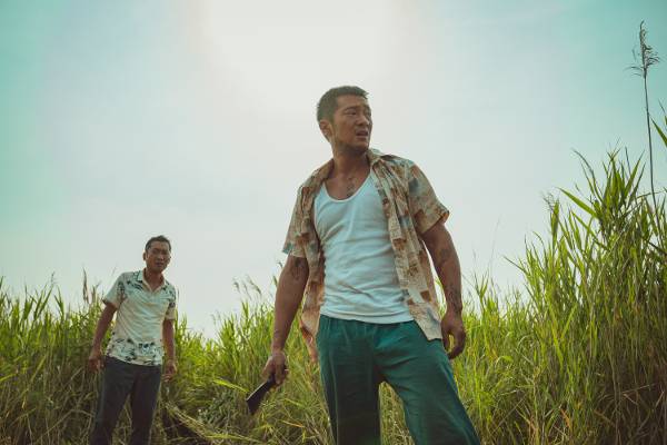 베트남 일대를 장악한 악당 강해상(오른쪽·손석구)이 흉기를 들고 벌판에 서 있는 모습.  메가박스중앙㈜플러스엠