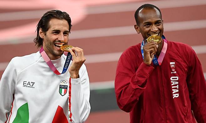 장마르코 탐베리(이탈리아·왼쪽)와 무타즈 에사 바심(카타르)이 지난해 도쿄올림픽 남자 높이뛰기에서 공동 금메달을 딴 뒤 메달을 깨물며 기념촬영을 하고 있다. 로이터연합뉴스