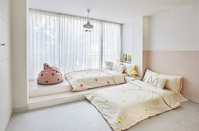 두 딸 주하·예하의 침실. 매트리스만 놓아 공간이 여유로워 보이는 효과를 준다. 베란다를 확장한 곳에 계단식 공간을 만들고 책장을 매립해 놀면서 책을 볼 수 있도록 했다. 침구와 빈백은 수제 베딩 브랜드 드플레잉 제품.