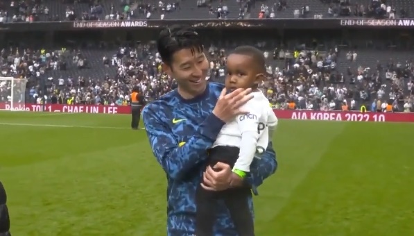 손흥민이 홈에서 치른 마지막 경기에서 승리한 후 동료 산체스의 아들을 안고 팬들에게 인사를 건네고 있다.