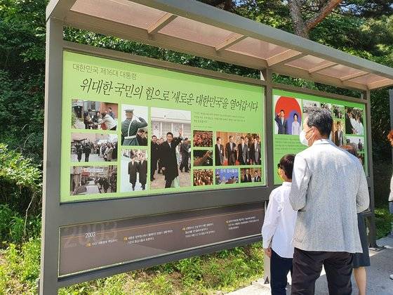지난 주말 경남 김해시 진영읍 봉하마을을 찾은 시민들이 묘역 인근에 설치된 야외전시대를 보고 있다. 안대훈 기자