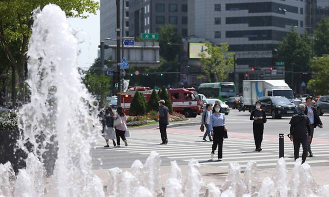 서울 최고기온이 23도까지 올라간 16일 시민들이 서울시청 앞 서울광장 분수대 옆을 걸어가고 있다. 연합뉴스