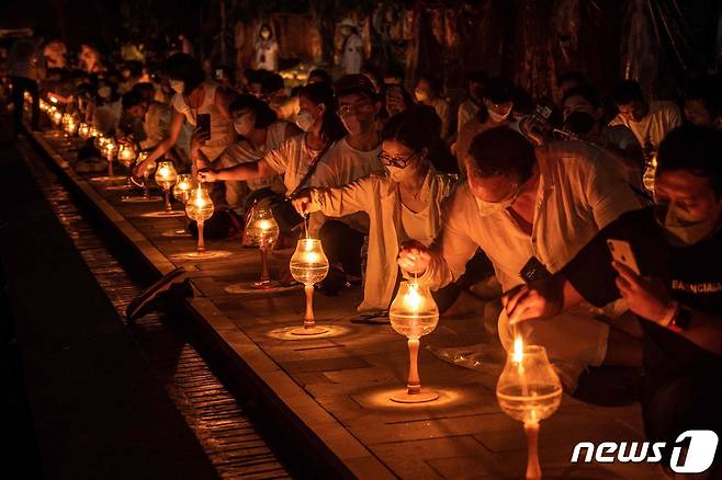 16일(현지시간) 인도네시아 자바의 마겔랑에 있는 보로부두르 사원에서 열린 베삭 데이 기념식에서 불교 승려와 신자들이 등불에 불을 붙이고 있다. © AFP=뉴스1 © News1 김예슬 기자