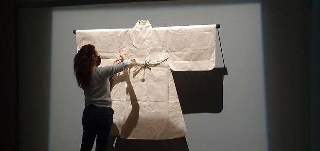 루브르 아부다비 기획전에 출품된 한국 전통 한지 도포(道袍)를 학예실 관계자가 벽면에 설치하고 있다. /미래에서온종이협회