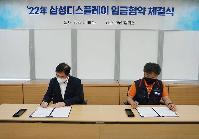 18일 삼성디스플레이 아산1캠퍼스에서 열린 '2022년 임금협약 체결식'에서 노사 위원들이 협약서에 서명하는 모습.(왼쪽부터 윤성희 인사팀장, 권상욱 노조 위원장)ⓒ삼성디스플레이