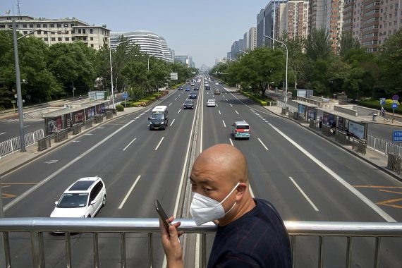 A man wearing a face mask stands on a bridge over an expressway in Beijing, Thursday, May 19, 2022. Parts of Beijing on Thursday halted daily mass testing that had been conducted over the past several weeks, but many testing sites remained busy due to requirements for a negative COVID test in the last 48 hours to enter some buildings in China's capital. (AP Photo/Mark Schiefelbein) /뉴시스/AP /사진=뉴시스 외신화상