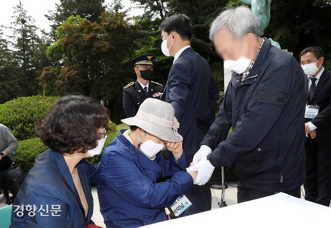 5·18민주화운동 당시 시위 진압에 참여했다가 돌진한 버스에 치여 순직한 경찰 정충길 경사의 유족인 박덕님씨(가운데)와 당시 버스를 운전한 배모씨가 19일 서울 동작구 국립서울현충원 경찰충혼탑 앞에서 열린 ‘함평경찰서 순직 경찰 유족과 사건 당사자 간 사과와 용서의 장’에서 서로의 손을 맞잡고 있다. 권도현 기자