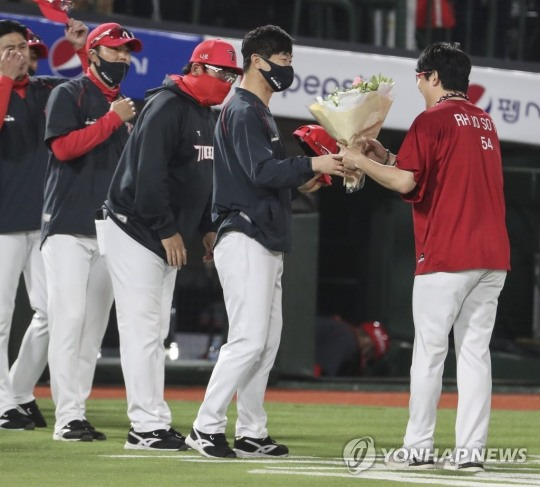 (부산=연합뉴스) 19일 부산 사직야구장에서 열린 프로야구 KIA 타이거즈와 롯데 자이언츠의 경기에서 최연소 150승 기록을 세운 KIA 양현종이 김종국 감독으로부터 꽃다발을 받고 있다.