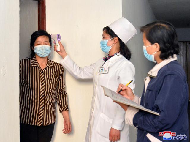북한 조선중앙통신이 제공한 사진에 17일 의료 관계자들이 코로나19 확산을 막기 위해 평양 주민의 체온을 점검하고 있다. 평양=AP 뉴시스