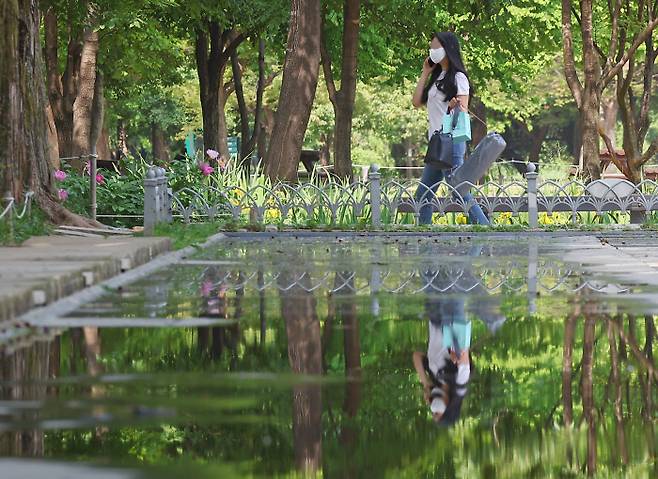 19일 오전 서울 성동구 서울숲에서 나들이를 즐기는 학생의 모습이 연못 고인물에 비치고 있다./연합뉴스