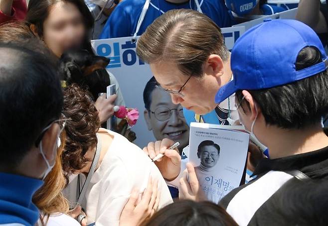 인천 계양을 국회의원 후보인 더불어민주당 이재명 총괄선대위원장이 20일 인천광역시 계양구 귤현동 일대에서 유세를 하며 한 지지자의 등에 사인을 한 뒤 인사하고 있다. ⓒ연합뉴스