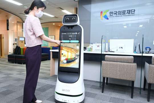 22일 한국의료재단 종합검진센터 직원이 LG전자의 클로이 가이드봇을 활용해 건강검진 안내를 받는 모습을 시연하고 있다. <LG전자>