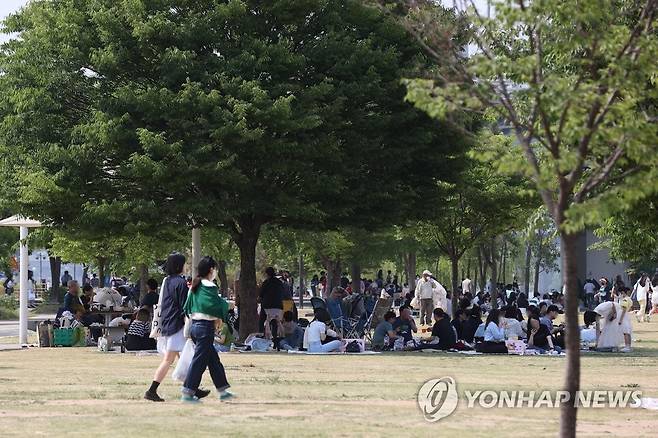 그늘 밑은 이미 만원 (서울=연합뉴스) 서대연 수습기자 = 서울 한낮 기온이 27도 안팎으로 더운 날씨를 보인 22일 오후 시민들이 서울 영등포구 여의도한강공원 나무 그늘 밑에 몰려 있다.  2022.5.22 dwise@yna.co.kr