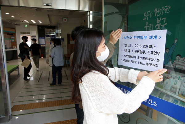 지난 23일 오전 광주 북구보건소 직원들이 코로나19 대응으로 중단됐던 민원업무와 진료업무를 재개한다는 안내문을 출입구에 붙이고 있다. 연합뉴스