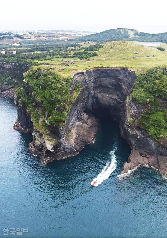 우도 '동굴투어' 보트가 쇠머리오름 아래 거대한 해식동굴을 돌아 나오고 있다.