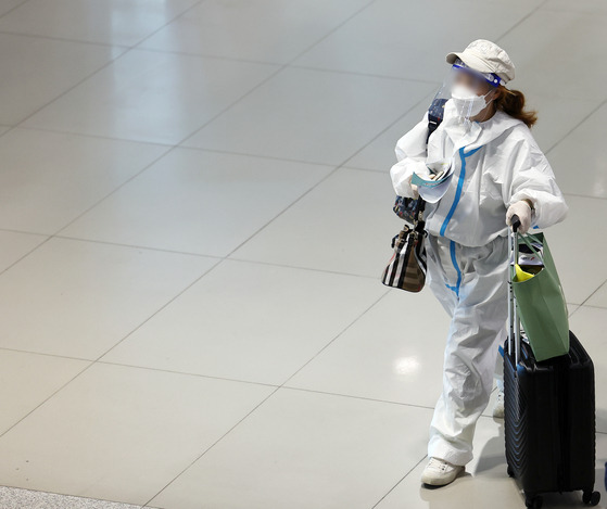 A traveler in protective gear walks in Incheon International Airport on Wednesday. [YONHAP]