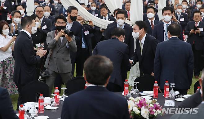 [서울=뉴시스] 전신 기자 = 윤석열 대통령이 25일 서울 용산 대통령실 청사 앞 잔디광장에서 열린 2022 대한민국 중소기업인대회에서 최태원 SK그룹 회장과 인사하고 있다. 2022.05.25. photo1006@newsis.com