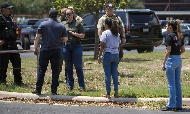 24일(현지시간) 미 텍사스주 유밸디의 롭 초등학교에서 총격이 발생해 경찰관이 주변에 모인 사람들과 얘기하고 있다. 유밸디=AP/뉴시스