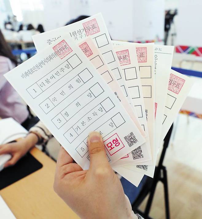 6·1 지방선거 사전투표를 하루 앞둔 26일 오후 인천국제공항 제1여객터미널에 마련된 사전투표소에서 인천 중구청 직원이 투표용지 모형을 들어 보이고 있다. /뉴스1