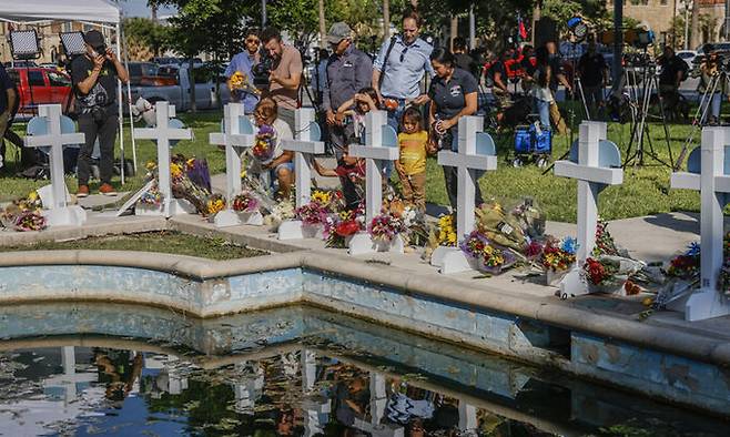 지난 26일(현지시간) 미국 택사스주 유밸디의 한 공원에 마련된 롭 초등학교 총기 난사 사건 피해자 추모 공간에서 사람들이 꽃과 메시지를 남기고 있다. 유밸디=EPA연합뉴스