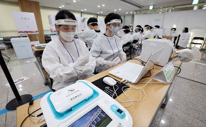 제8회 전국동시지방선거 사전투표 이틀째인 28일 서울 용산구의회에 마련된 사전투표소에서 투표사무원과 관계자들이 코로나19 확진·격리자 사전투표를 위해 방호복 등을 착용하고 있다. (사진=연합뉴스)