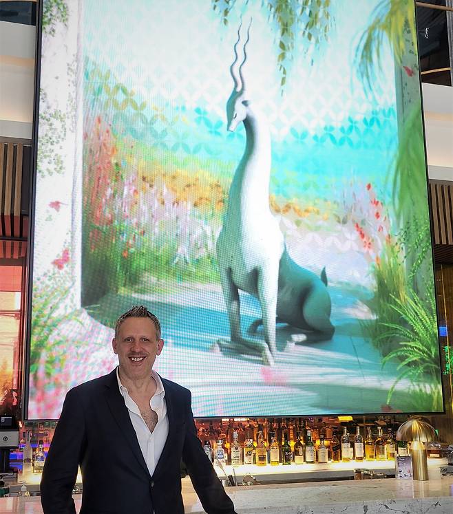 '니오'의 롭 앤더스 공동창업자 겸 CEO가 24일 서울 용산구 몬드리안호텔 1층 대형 스크린에 전시되고 있는 앨리 매거자이너의 디지털 아트 '임팔라 가든' 앞에서 환하게 웃고 있다. /장우정 기자