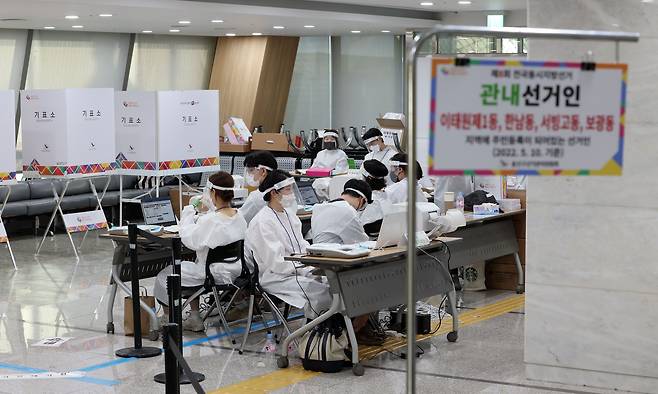 제8회 전국동시지방선거 사전투표 이틀째인 28일 서울 용산구의회에 마련된 사전투표소에서 투표사무원과 관계자들이 코로나19 확진·격리자 사전투표를 위해 방호복 등을 착용한 후 대기하고 있다. /연합뉴스