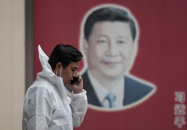중국 상하이시에서 방호복을 입은 중국 정부통제요원이 시진핑 중국 국가주석의 사진이 걸린 거리에서 통화를 하고 있다. EPA연합뉴스