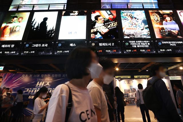 서울 시내의 한 극장 앞에서 1일 관객들이 ‘범죄도시 2’를 포함한 최신작 포스터들을 둘러보고 있다. 연합뉴스