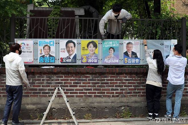 제8회 전국동시지방선거 공식 선거운동이 시작된 19일 서울 종로구 대학로에서 관계자들이 선거벽보를 부착하고 있다. /사진=이기범 기자 leekb@