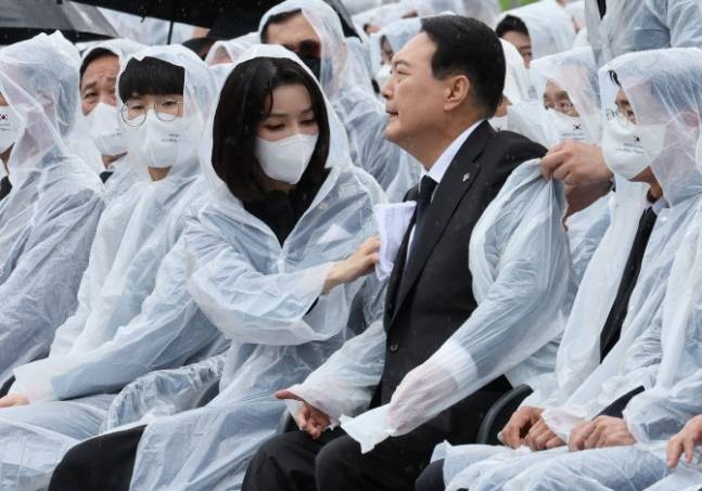 김건희 여사(왼쪽에서 네번째)가 지난 6일 오전 서울 동작구 국립서울현충원에서 열린 ‘제67회 현충일 추념식’에서 비에 젖은 남편 윤석열 대통령(〃 다섯번째)의 옷을 닦아주고 있다. 연합뉴스