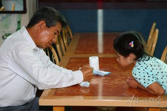 2008년 고(故) 노무현 전 대통령이 경남 김해 진영읍 봉하마을에서 산책하던 중 매점에 들러 손녀 노서은양에게 꽁꽁언 아이스크림을 손으로 녹여주고 있다. [사진 노무현사료관]