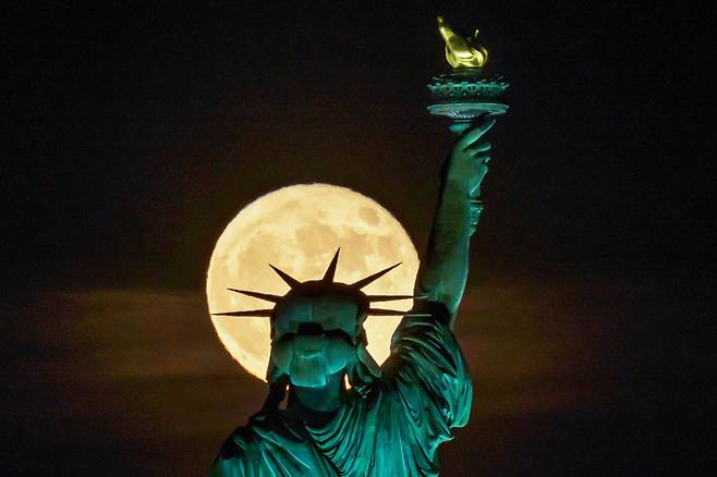 14일(현지 시각) 미국 뉴욕의 자유의 여신상 뒤로 보름달이 보인다. / AP 연합뉴스