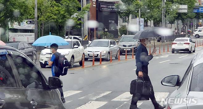 [광주=뉴시스] 류형근 기자 = 지난 14일 오전 광주 남구 봉선동 도로 횡단보도에서 학생과 직장인이 우산을 쓰고 걷고 있다.  2022.06.14. hgryu77@newsis.com