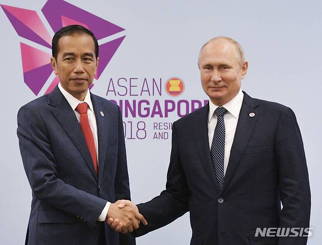 [싱가포르=AP/뉴시스]조코 위도도 인도네시아 대통령(왼쪽)이 지난 2018년11월14일 싱가포르에서 열린 아세안(ASEAN·동남아시아국가연합) 정상회의에 앞서 악수하며 기념 사진 촬영에 응하고 있다. 2022.06.21.