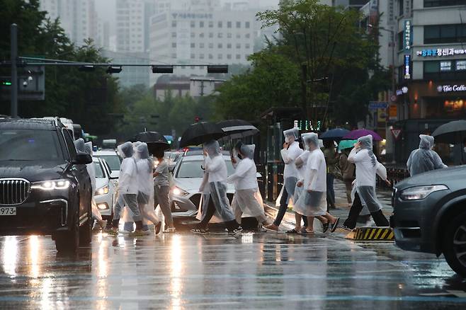 23일 오후 서울 종로구 광화문 횡단보도로 비옷과 우산으로 비를 가린 시민들이 건너가고 있다. 백소아 기자