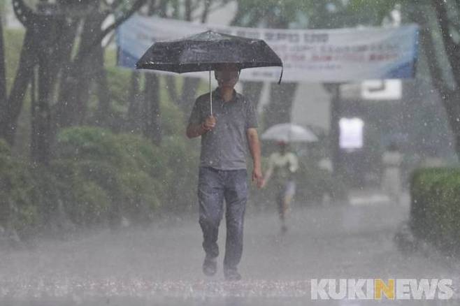 전국에 장마가 시작된 23일 오후 서울 송파구 석촌호수에서 우산을 쓴 시민들이 걸어가고 있다.