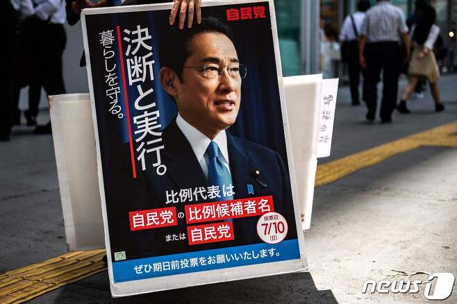 24일 자민당 선거운동원이 요코하마역 앞에서  기시다 후미오 일본 총리의 선거 유세용 포스터를 들고 있다. © AFP=뉴스1