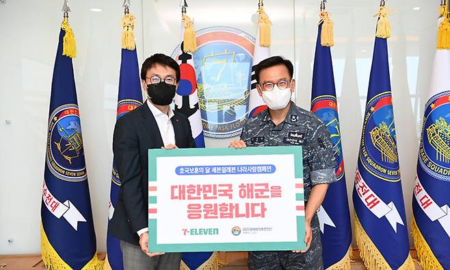 강성두 세븐일레븐 커뮤니케이션 본부장(왼쪽)이 안상민 해군 환태평양훈련전단장에게 후원물품을 전달하며 기념 촬영을 하고 있다. 세븐일레븐 제공