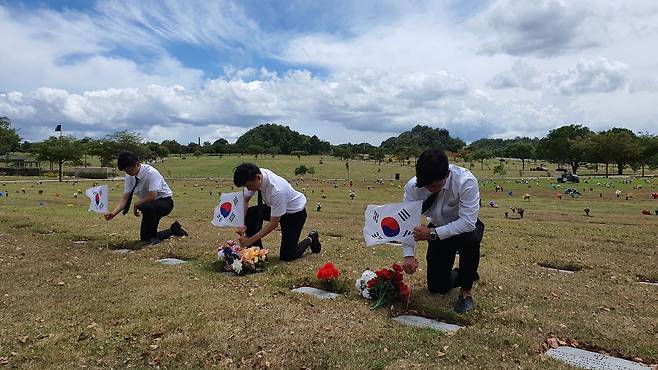 IYF 굿뉴스코 푸에르토리코 해외봉사단원들이 지난 24일(현지 시각) 푸에르토리코 바야몬시 국립묘지를 찾아 6·25 참전용사들의 묘지에 태극기를 꽂고 있다./IYF 굿뉴스코 푸에르토리코 해외봉사단