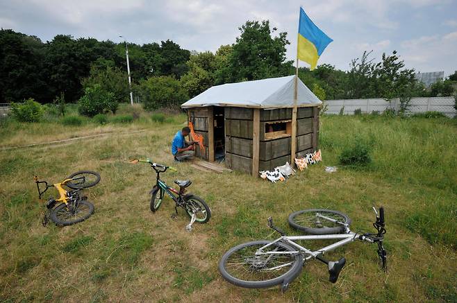 지난 21일(현지 시각) 우크라이나 체르니히우 외곽의 한 마을에서 한 남성이 탄약 상자로 어린이를 위한 놀이용 오두막을 만들고 있다. /AFP 연합뉴스